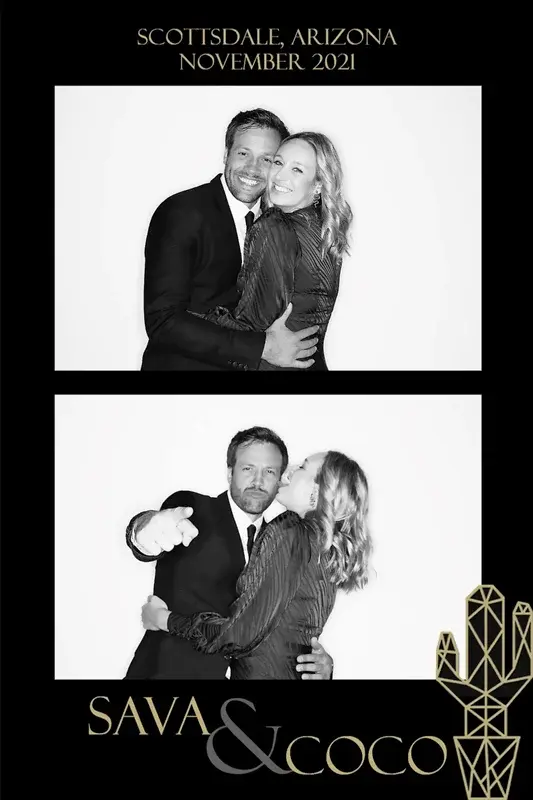 Couple posing and embracing in a black-and-white photo booth at a wedding.